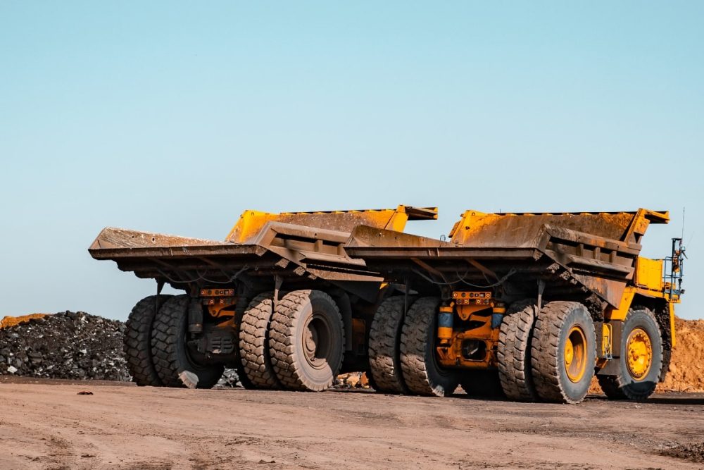 Rear view of two large yellow mining trucks.